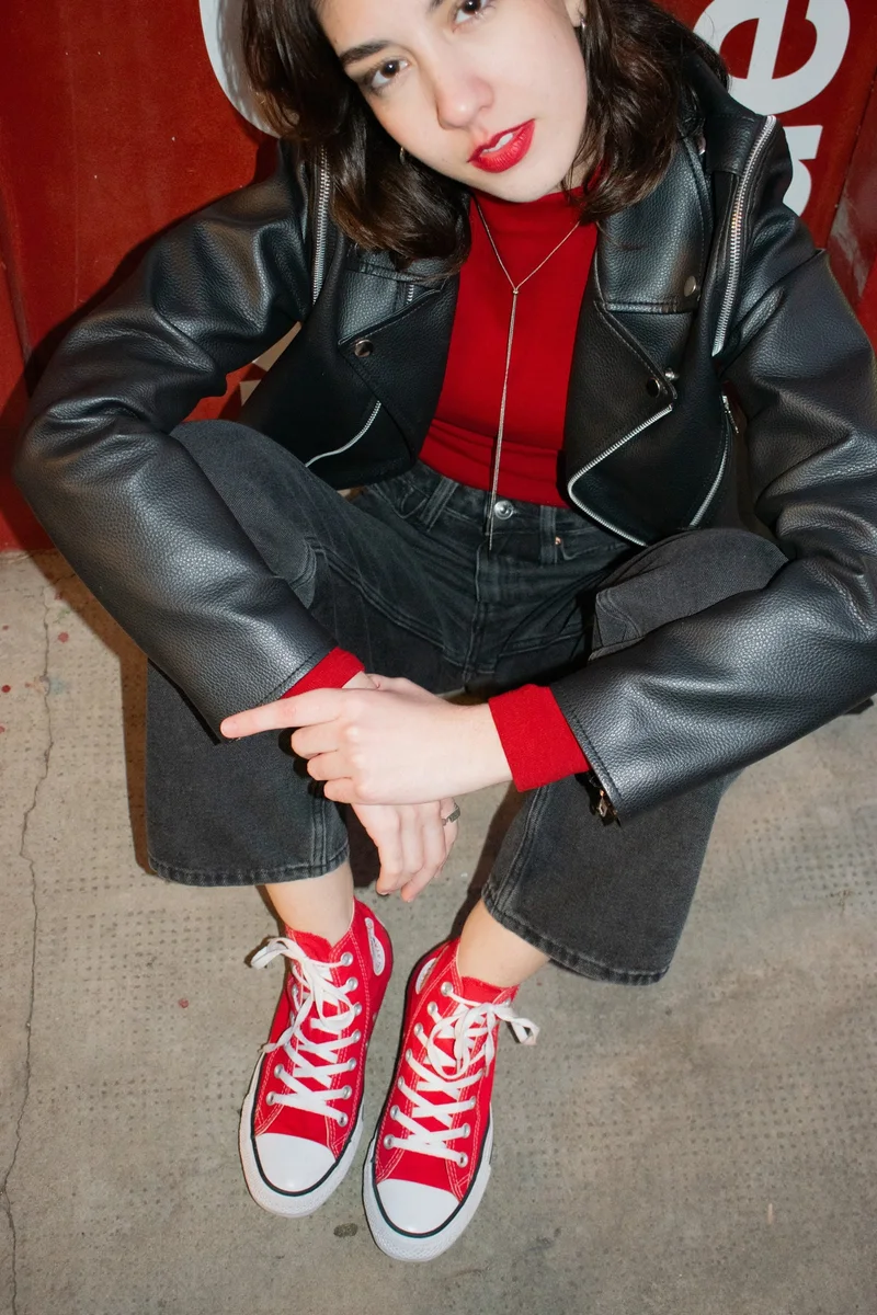 Modelo con campera de cuero y labios rojos frente a una pared roja