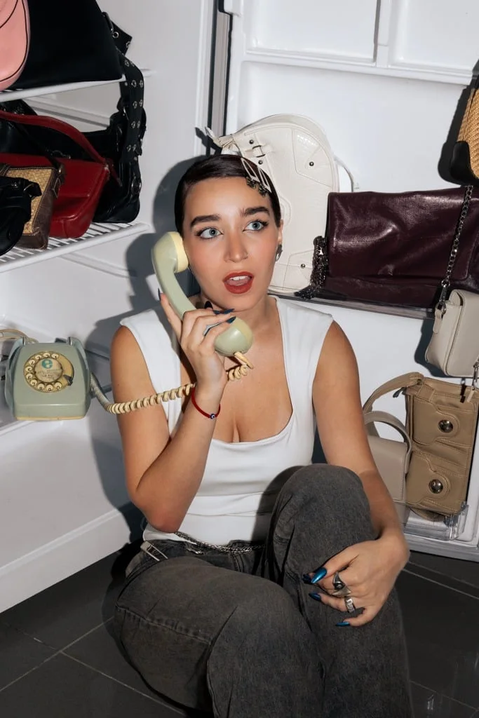 Modelo sentada dentro de una heladera hablando por un teléfono antiguo