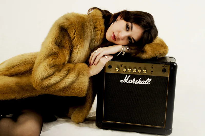 Modelo con tapado de piel apoyada sobre un amplificador Marshall