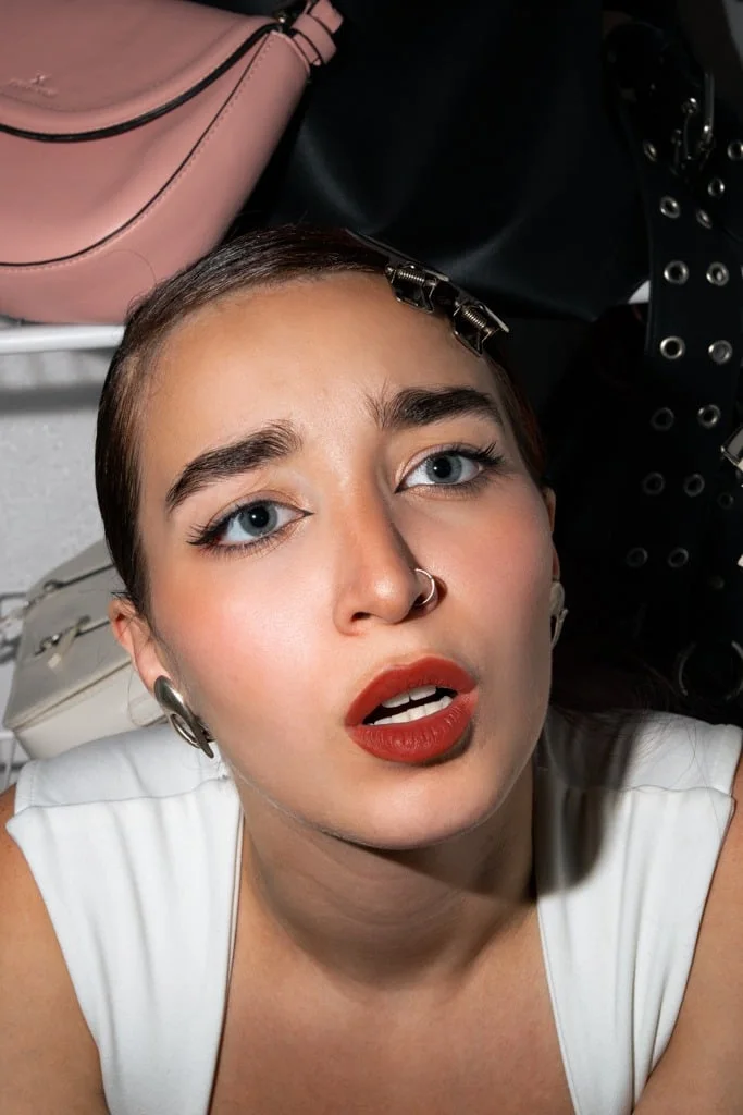 Primer plano de la modelo con labios rojos dentro de una heladera con carteras